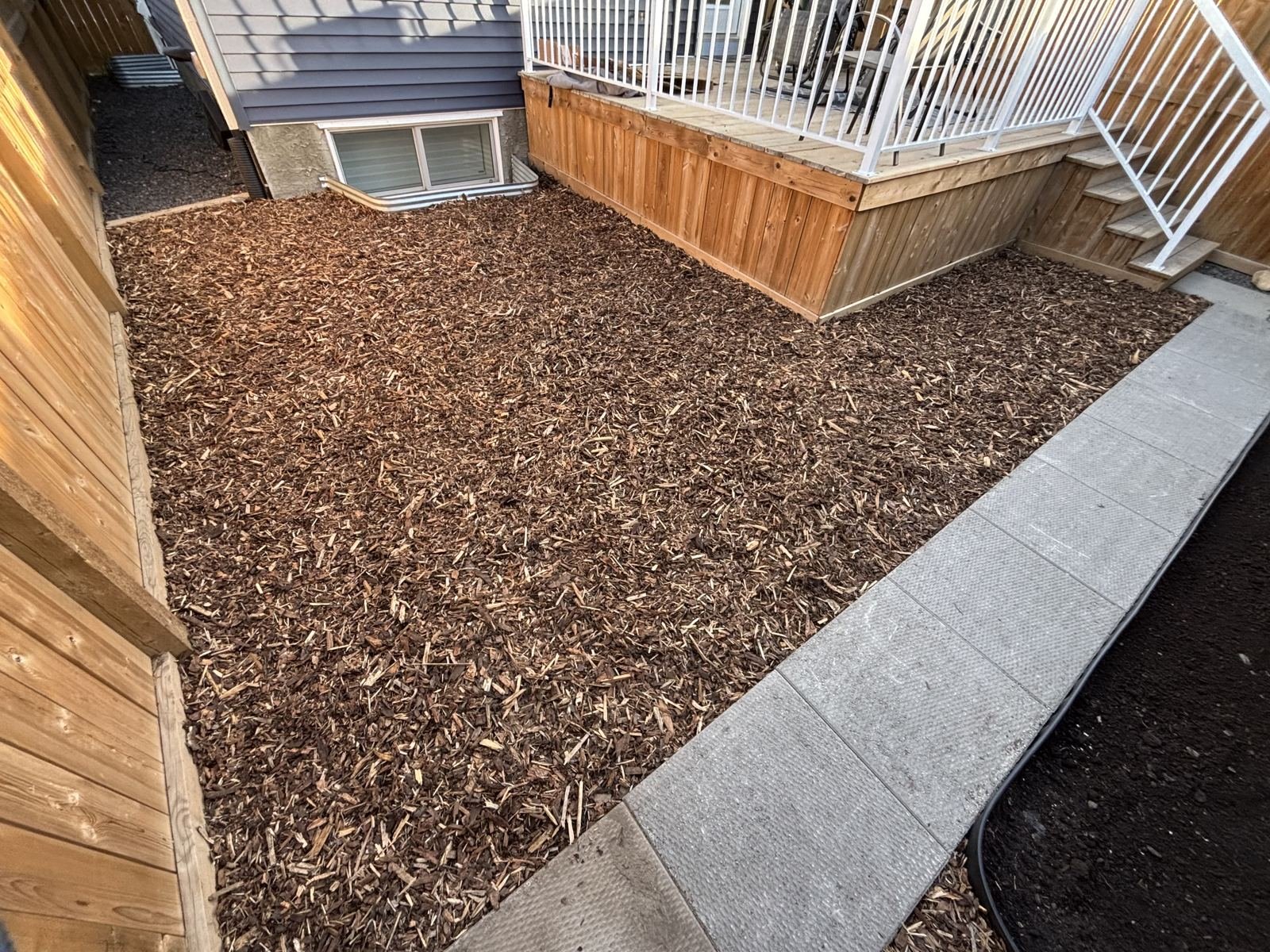 Fresh mulch bed under a backyard deck